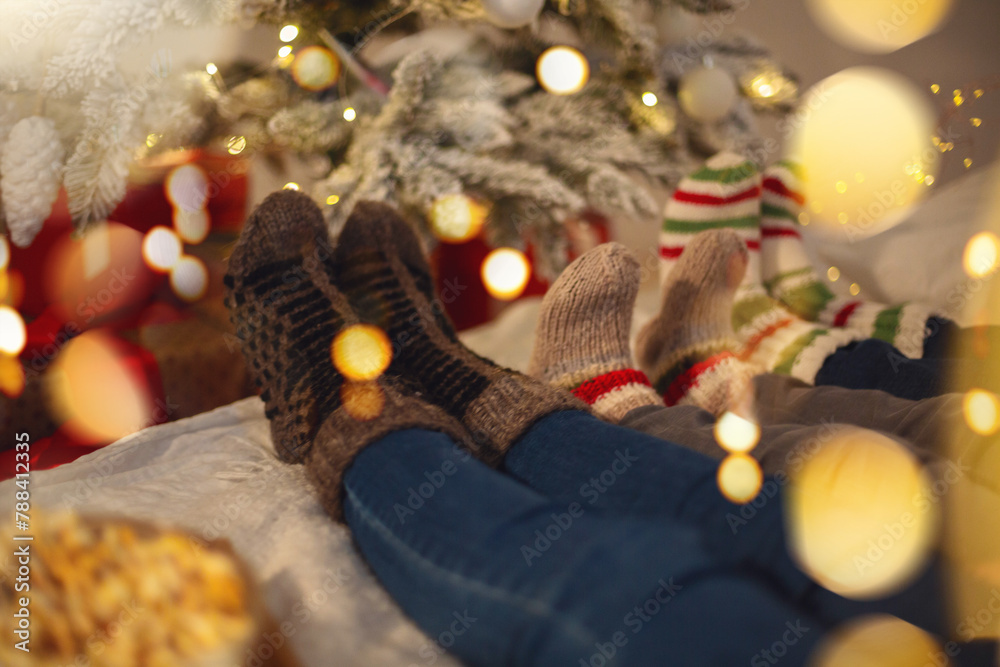 Lazy family parents and kid wearing warm woolen socks resting at home on cozy Christmas morning