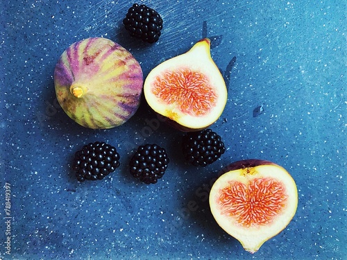figs and blackberries, cut fresh figs, dark blackberry fruits on a wooden board, fresh vitamins