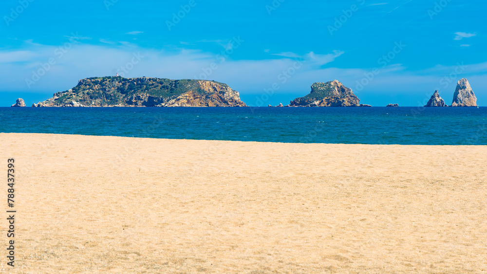 Playa dorada en primer plano con las Islas Medas al fondo, un destacado paraje natural en Estartit, Cataluña, bajo un cielo azul de primavera. - obrazy, fototapety, plakaty 