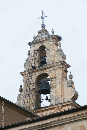 View of a stone bell tower with two bells. Stork nest on a bell tower.