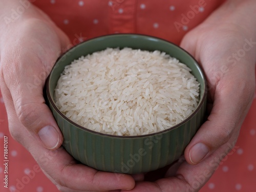 Woman holding green bowl full of rice in her hands. Close-up