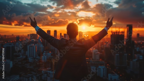 A man in a suit is standing on a rooftop, holding his hands up in the air and looking out over the city. Concept of excitement and accomplishment, as if the man has just achieved something great