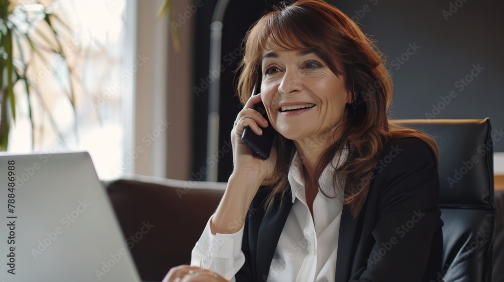 A woman is talking on her cell phone while sitting at a desk A woman is talking on her cell phone while sitting at a desk