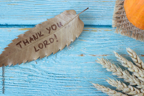 Thank You LORD, handwritten text on dry autumn leaf with pumpkin and wheat on wooden table. Top view. Christian thanksgiving, gratitude, and praise to God Jesus Christ. Biblical concept.