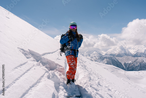 Woman snowboarder resting on slope of powdery snow in high mountains avalanche-prone area. Freeride at ski resort, Snow splashes trail,  mountain peaks view