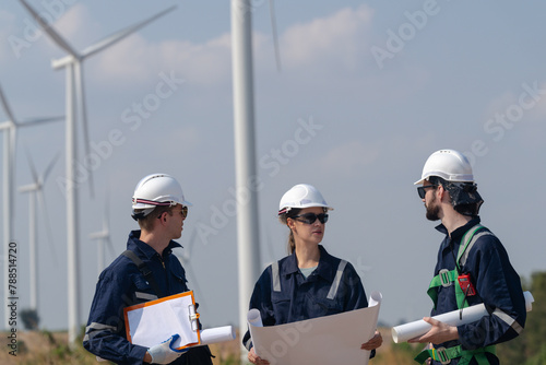 Engineers man and woman inspecting construction of WIND TURBINE FARM. WIND TURBINE with an energy storage system operated by Super Energy Corporation. Workers Meeting to check AROUND THE AREA.