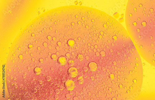 Beautiful cosmetic background. Golden orange yellow abstract oil bubbles or face serum background. Oil and water bubbles macro photography.