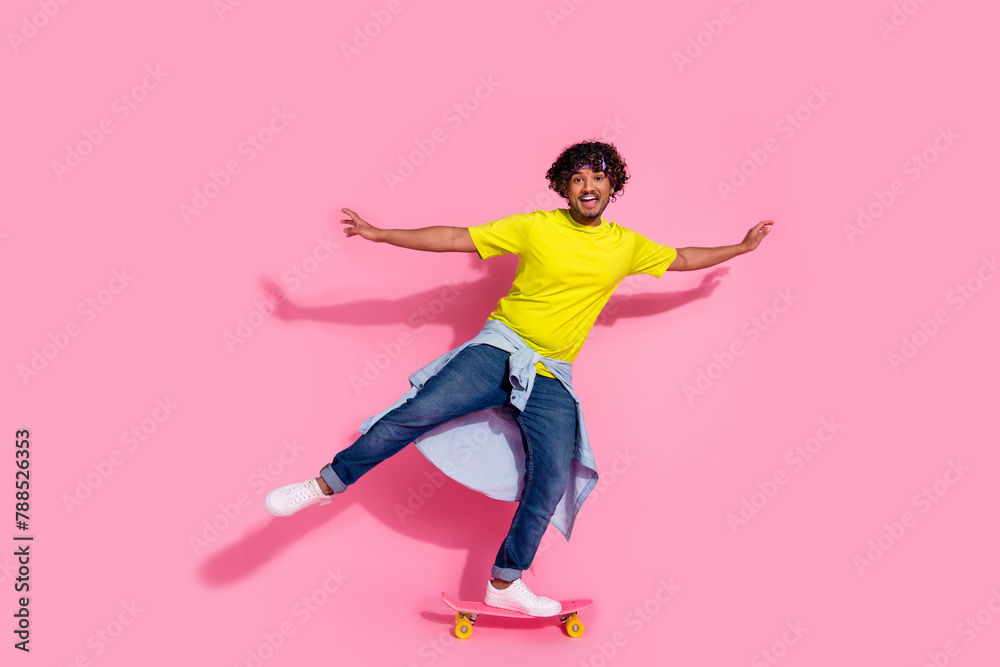 Photo of funny glad cheerful man wear trendy yellow clothes riding fast pennyboard isolated on pink color background