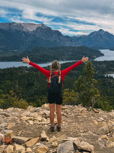 A woman stands on a mountain top, arms outstretched, with a backpack on her back. Concept of freedom and adventure, as the woman is embracing the beauty of nature