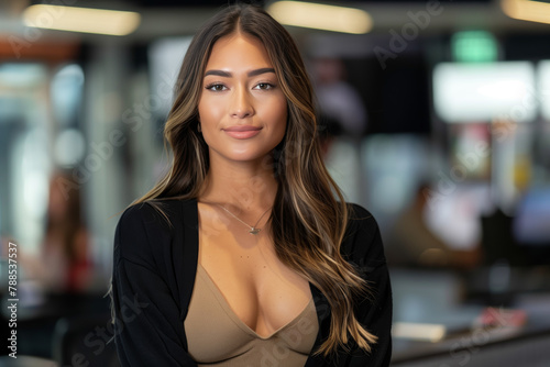 Brunette Hispanic entertainment personality or celebrity woman with long brown hair and a black sweater posing in a news TV studio in south america