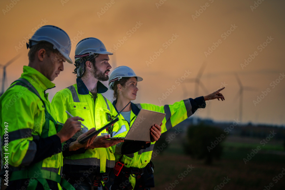Team Engineers men and woman checking and inspecting on construction with sunset sky. people operation. Wind turbine for electrical of clean energy and environment. Industrial of sustainable. Team Engineers men and woman checking and inspecting on construction with sunset sky. people operation. Wind turbine for electrical of clean energy and environment. Industrial of sustainable.