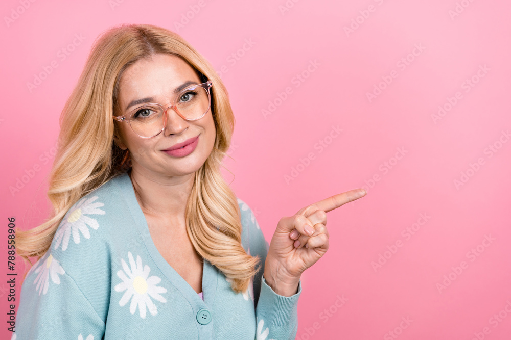 Portrait of optimistic person with curly hairstyle wear blue cardigan in eyewear directing empty space isolated on pink color background Portrait of optimistic person with curly hairstyle wear blue cardigan in eyewear directing empty space isolated on pink color background