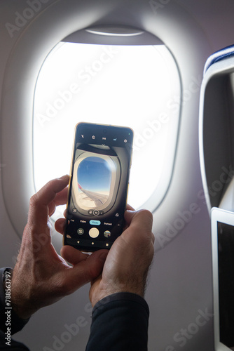 man taking photos through plane window