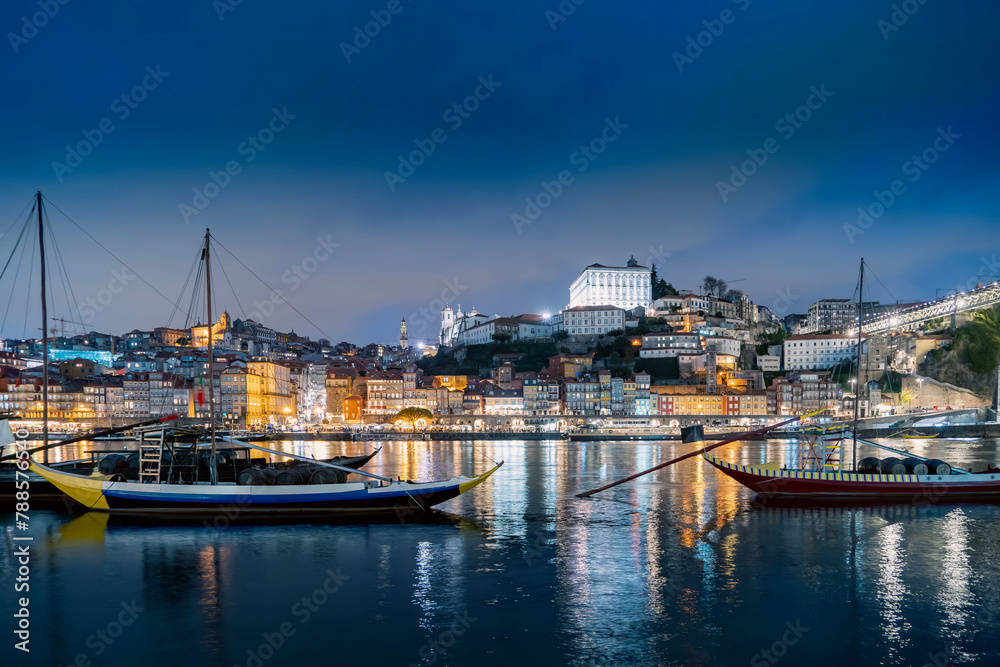 Porto, Portugal old town on the Douro River with traditional rabelo boats at night. With wine barrels from the port on the Douro River, Ribeira I in the background, Porto, Portugal.