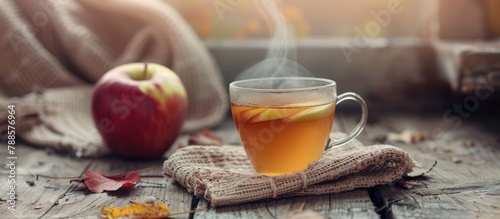 Autumn bounty of the fall harvest. A steaming cup of apple tea to kickstart the day. Cozy seasonal beverage for the autumn. Empty space against a wooden backdrop.