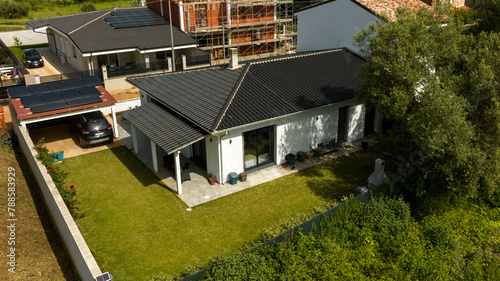 Aerial view on a white villa with garden. There is a car parked but no one is home.