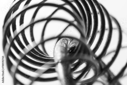 Metal spring coiled, black and white macro shot, soft focus, abstract industrial art photo