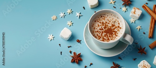 A mug and the necessary components for preparing a warm winter beverage, set against a blue backdrop. Overhead perspective with space for additional content.