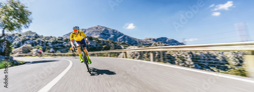 Mature Adult on a racing bike climbing the hill at mediterranean sea landscape coastal mountain road - mallorca mountains photo