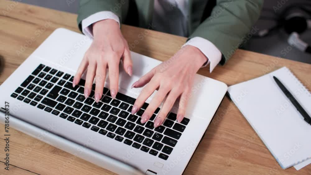 young woman working at home typing on a laptop keyboard and making notes in a notepad, close-up young woman working at home typing on a laptop keyboard and making notes in a notepad, close-up