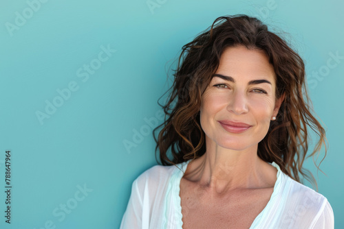 A woman is smiling in front of a blue background © MagnusCort