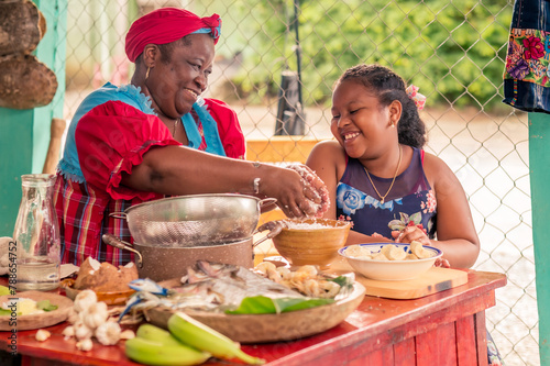 Foto African-American mother teaches her little daughter how to cook Tapado, traditional Garifuna dish- Ingredients for Tapado on the kitchen table