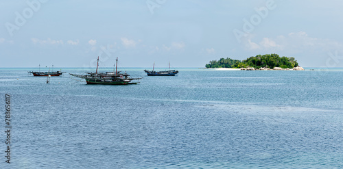 Tanjung Binga fishing village beach with fishing boats in front of Kera Kecil Island and other islands Belitung, Bangka Belitung, Indonesia photo