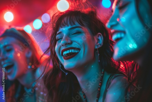 Young women laughing and having fun at a party in neon red and blue light