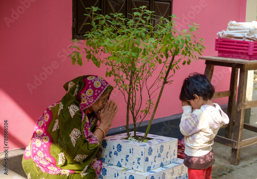 Grandmother teaching her granddaughter to respect holy basil as a part of hindu culture 