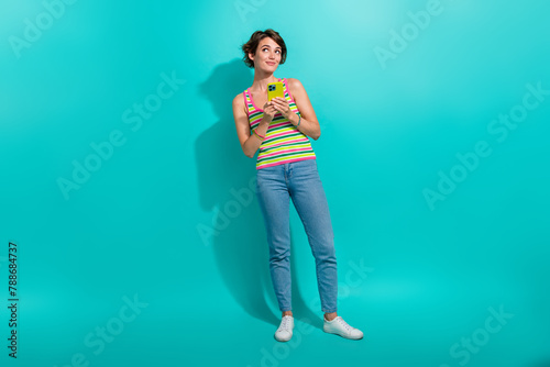 Full body photo of creative minded lady use smart phone look empty space isolated on teal color background