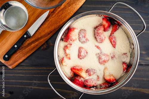 Macerating Fresh Strawberries in a Large Pot: Halved and sliced ripe strawberries covered in organic cane sugar in a saucepan to macerate