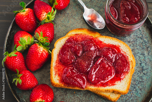 Slice of Toast Covered in Homemade Strawberry Preserves: Sliced and toasted white bread and homemade strawberry preserves with large pieces of fruit