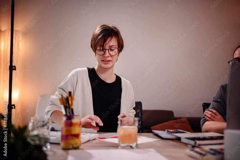 An artist examines her work with a critical eye, surrounded by the cozy glow of a studio lamp, indicative of the creative process An artist examines her work with a critical eye, surrounded by the cozy glow of a studio lamp, indicative of the creative process