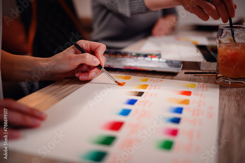 A close-up of an artist's hand as they blend watercolors on paper, showcasing the delicate art of color mixing and the tools of the trade photo