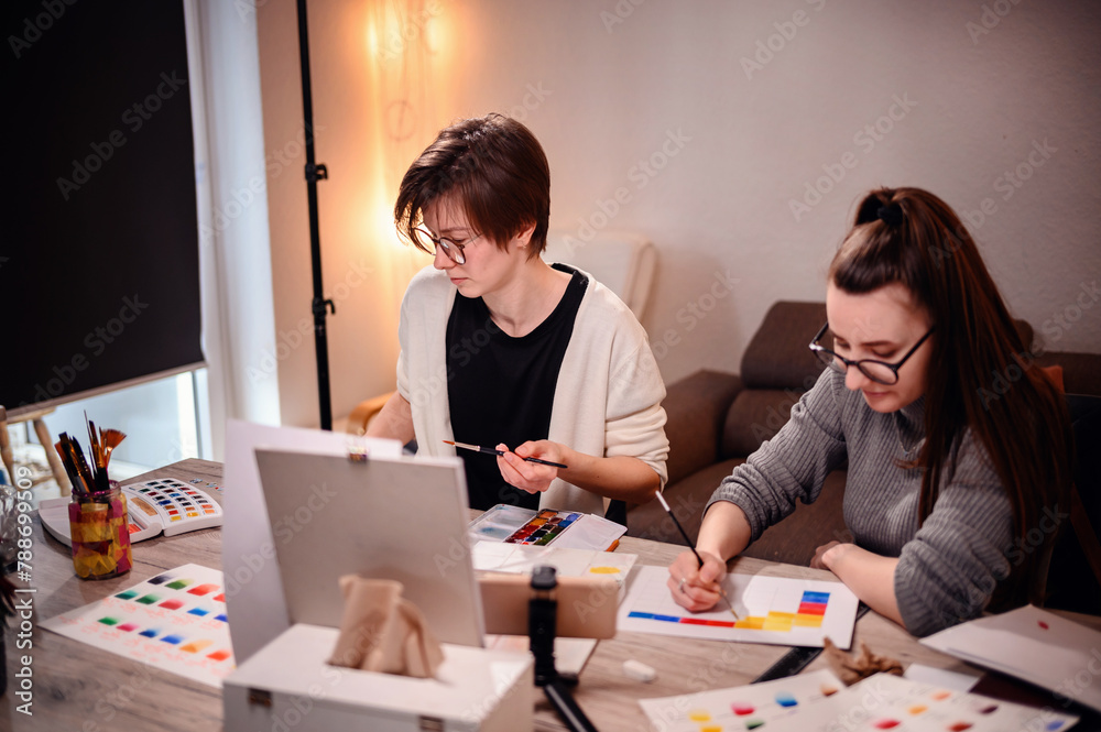 Two artists intently craft a color narrative, one with brush in hand, the other with pen poised, against the backdrop of a warm studio light. Two artists intently craft a color narrative, one with brush in hand, the other with pen poised, against the backdrop of a warm studio light.