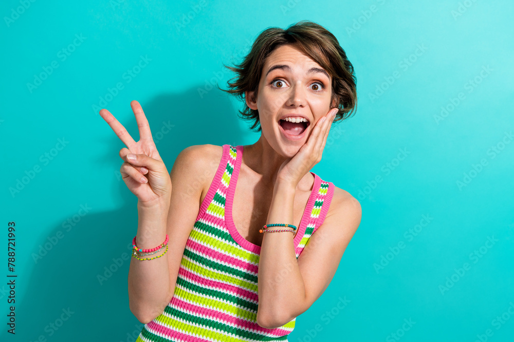 Portrait of excited funny lady person showing v sign symbol open mouth hand on cheek wear singlet isolated teal color background Portrait of excited funny lady person showing v sign symbol open mouth hand on cheek wear singlet isolated teal color background