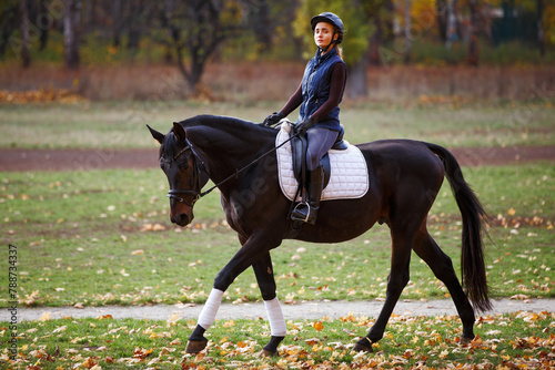 Young pretty girl riding horse in autumn park. © skumer