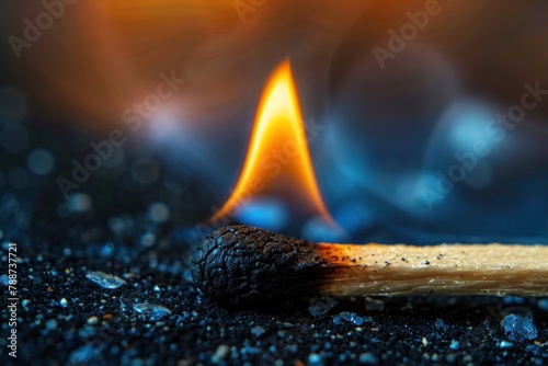 a burning match lies on a dark surface