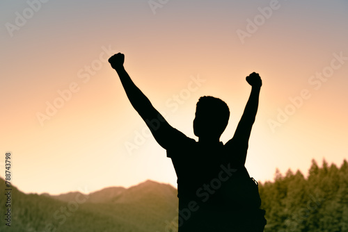 Photography Adventurous man in forest mountain sunrise looking up to the sky with fist up, n