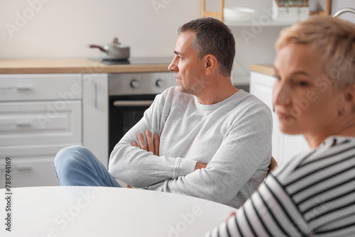 Offended mature man quarreling with his wife in kitchen