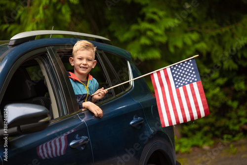 Little happy boy waving American flag out of car window. Patriotism, 4th of July calibration concept. 
