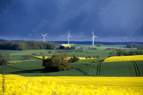 Agriculture et éoliennes sur fond de ciel orageux.