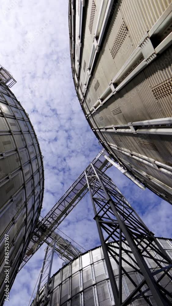Metal tanks of elevator. Grain-drying complex outdoors. Commercial grain silos on sky background. Steel storage for agricultural harvest. Close-up. Vertical video
