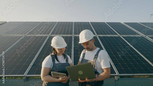 Two workers with a laptop discuss the installation and efficiency of solarpanels