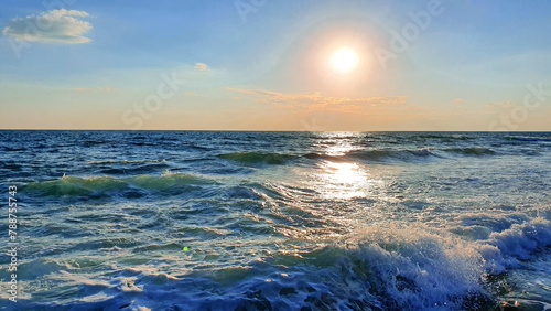 Colorful sunset with large sun under the sea waves.