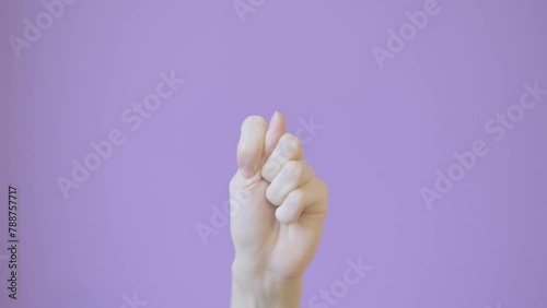 Close up woman hand shows fig sign isolated on lilac background. Fig gesture photo