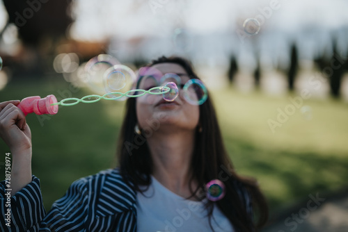 An adult woman enjoys a leisurely day in the park, blowing bubbles and relishing the simple joys of life under a clear sky.