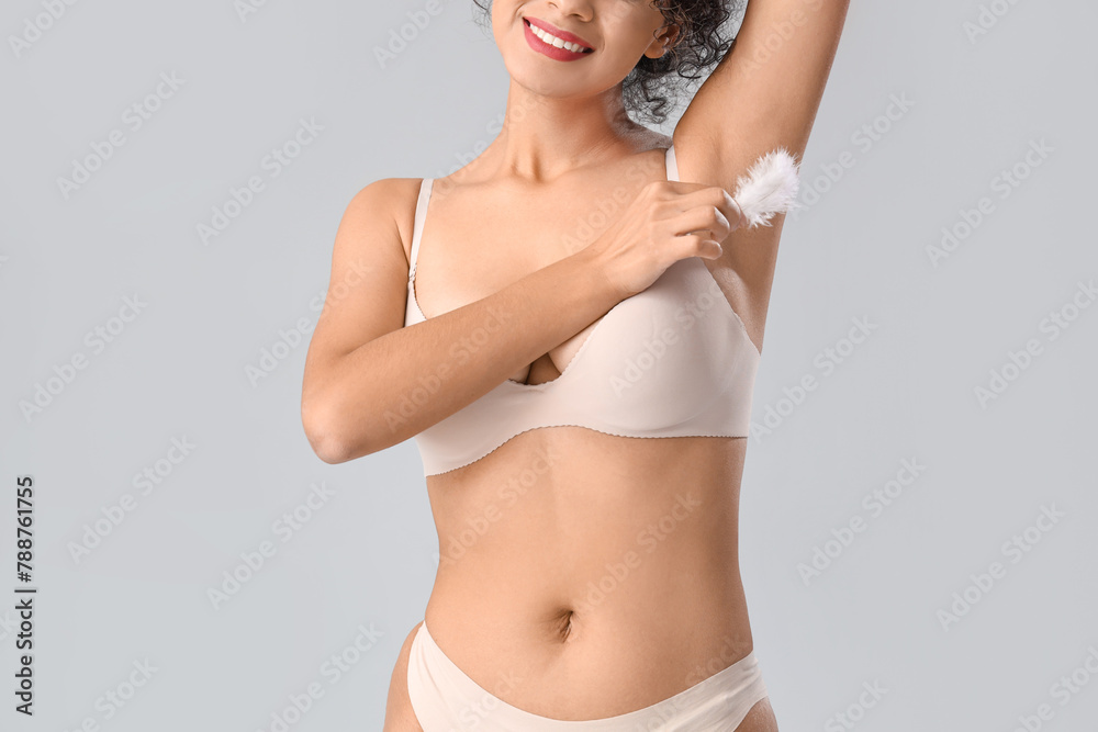 Naklejka premium Beautiful young woman with soft feather on grey background. Hair removal concept