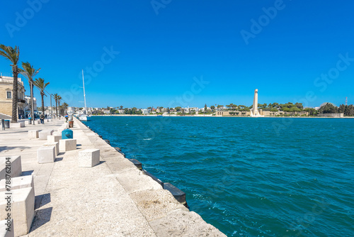 Lungomare in Brindisi, a pedestrian walkway next to the beach and surrounding old town. Row of palms are visible on a warm spring day