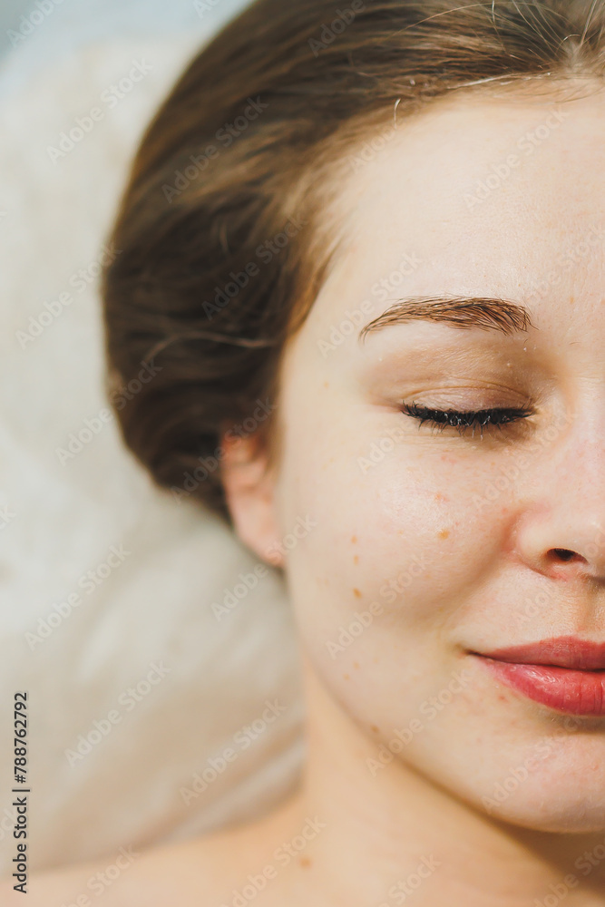 Close-up of a young woman's face during a facial cleansing procedure in a beauty salon. A beautician in black gloves wipes a client's face with a napkin. Therapeutic facial skin care. Close-up of a young woman's face during a facial cleansing procedure in a beauty salon. A beautician in black gloves wipes a client's face with a napkin. Therapeutic facial skin care.